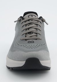 Baskets de sport grises avec une tige texturée, des détails perforés, des lacets plats et une semelle en caoutchouc noir. Design minimaliste avec des surfaces lisses.