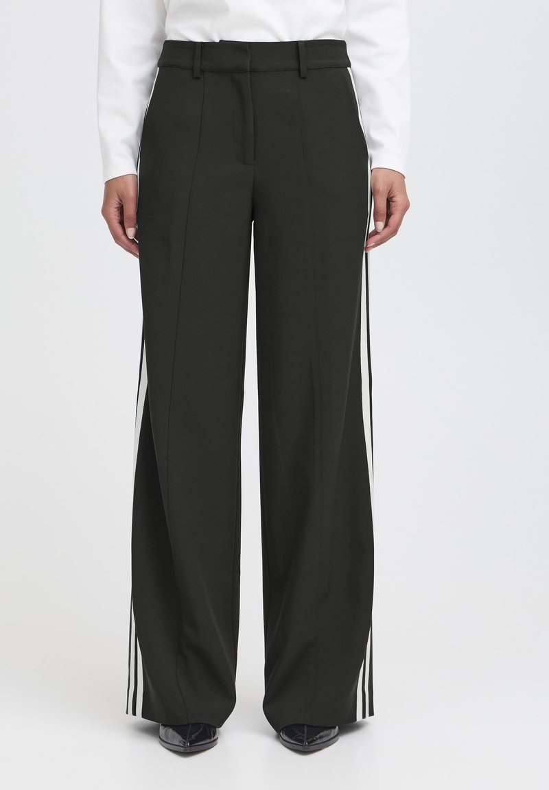 Pantaloni neri a gamba larga con una texture liscia, con strisce laterali bianche e una vita alta. Il tessuto appare leggero e tagliato su misura.