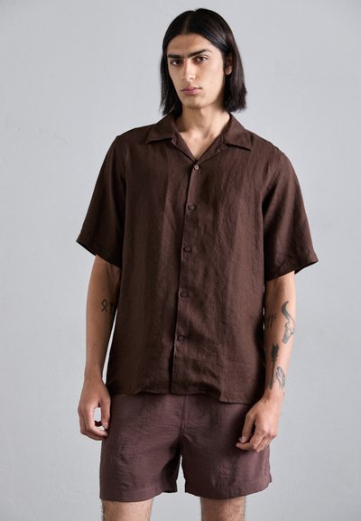 Chemise en lin marron à manches courtes avec un col camp, un bouton sur le devant et une coupe décontractée, associée à un short marron assorti.