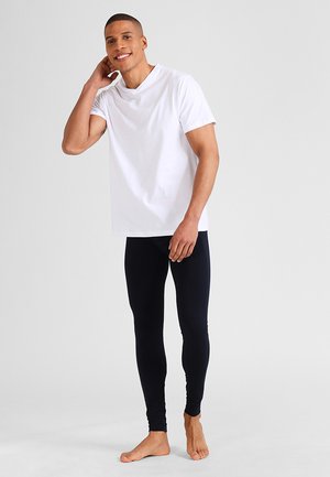 T-shirt en coton blanc avec un col rond associé à un legging noir près du corps. La tenue présente un design simple et minimaliste.