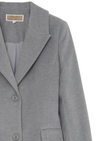 Blazer grigio con texture, a revers a punta, due bottoni e tasche laterali. Il tessuto presenta un motivo sottile, mostrato parzialmente aperto per rivelare la fodera interna.