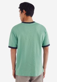 Grøn bomulds t-shirt med korte ærmer, udstyret med en marineblå ribbede krave og mansjetter. Glat tekstur med et afslappet pasform-design.