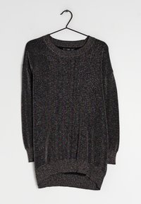 Pull noir à manches longues avec des fils métalliques, encolure ronde, poignets et ourlet côtelés, présentant une coupe ample et des fentes latérales.