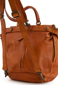 Sac à dos en cuir marron avec des sangles ajustables, des poignées supérieures et des accessoires en métal. Il dispose d'une poche zippée à l'avant et d'une finition texturée.
