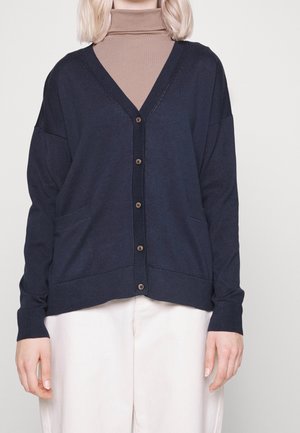 Cardigan blu navy con scollatura a V, chiusura con bottoni e due tasche frontali. Tessuto in maglia morbida con polsini e orlo a coste.
