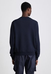 Felpa blu in misto cotone, con collo a girocollo, polsini e orlo ribattuti. Presenta una vestibilità comoda e una texture liscia.
