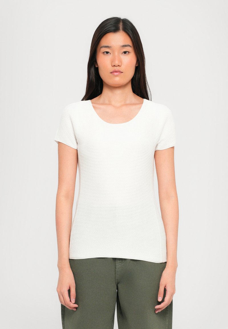 Witte top met korte mouwen en een ronde hals, van gestructureerde rib stof, met een getailleerd ontwerp. Gecombineerd met olijfgroene pantalons.