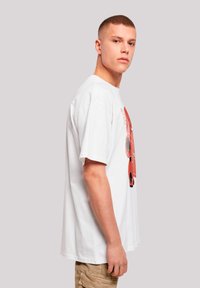 White cotton T-shirt featuring a graphic print design in red and black. Short sleeves and a relaxed fit, with a crew neckline.