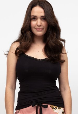 Zwarte camisole met delicate kantafwerking, aansluitend ontwerp en een gladde textuur. Gedragen met lichtroze gemusterde onderkant met een trekkoord.