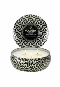 Rund Voluspa-ljus i en metallburk med svart och guldmönster, med tre veker och märkt "Crisp Champagne."