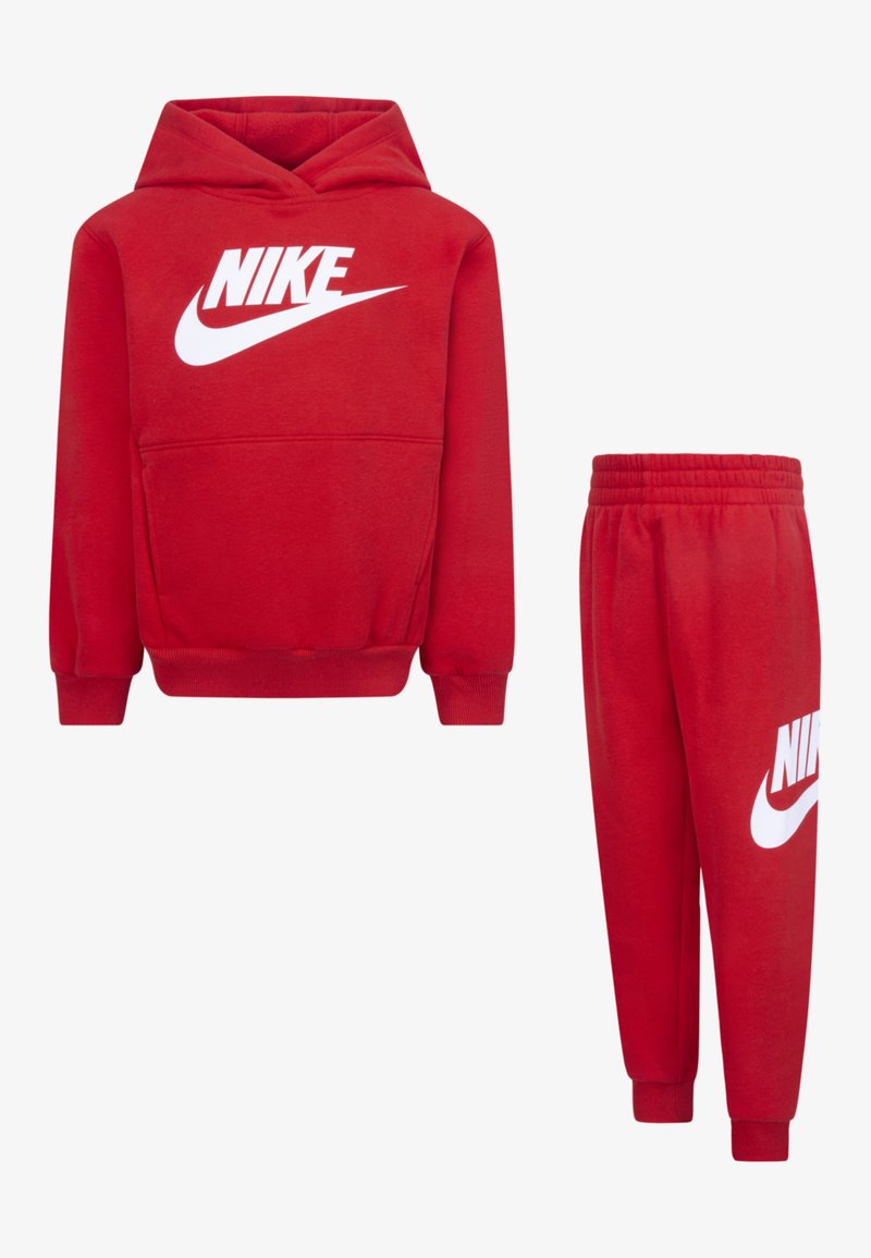 Sarkans Nike kapuces džemperis ar baltu logo, kangaroo kabatu un ribinātu apakšmalu. Atbilstošas sarkanas sporta bikses ar baltu logo, elastīgu jostasvietu un sašaurinātiem galiem.
