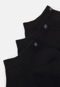 Schwarze Socken mit gerippter Textur und enganliegender Passform. Merkmale ein kleines weißes Logo am Bund, das ein einfaches und minimalistisches Design präsentiert.