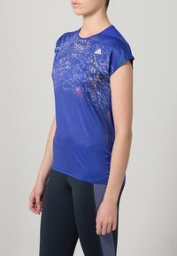 Short-sleeve athletic shirt in vibrant blue with a textured, abstract design in lighter hues; features Adidas logo on the left chest.