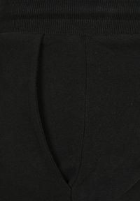 Zwarte sweatpants van zacht materiaal met een geribbelde tailleband en een taps toelopend ontwerp. Opvallende diepe zijzakken.