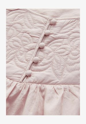 Ljust rosa tyg med blommönsterbroderi, fem tygklädda knappar och rynkad textur vid fållen. Mjukt, slätt material.