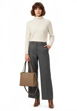 Woman wearing a cream turtleneck sweater, gray wide-leg pants, brown ankle boots, holding a brown leather handbag.