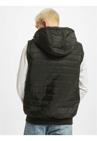 Zwarte gewatteerde vest met een capuchon, voorzien van horizontale gestikte secties en ribbelzoom. Gemaakt van glad, glanzend materiaal.