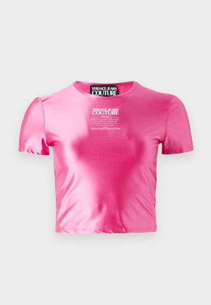 T-shirt rose raccourci en tissu lisse et brillant. Présente des manches courtes et un col rond avec un logo en texte blanc au centre.