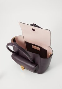 Sac à main en cuir violet avec une finition texturée, quincaillerie dorée, une ouverture sur le dessus et un intérieur rose clair comportant une poche pour cartes.