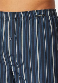 Pantaloni corti da uomo con un motivo a righe verticali blu navy e azzurro. Realizzati in tessuto morbido con una vita elastica e dettagli con un singolo bottone.