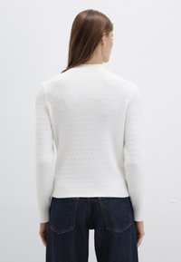 Weißer strukturierter Pullover mit langen Ärmeln und rundem Ausschnitt, mit einem gestrickten Muster und einer leicht taillierten Silhouette.