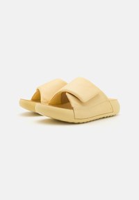 Sandali gialli con materiale morbido e una fascia superiore ampia. Il design presenta una punta arrotondata e una suola flessibile per il massimo comfort.