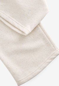 Helles cremefarbenes Gewebe mit einem gesprenkelten Muster in Pastellfarben. Glatte Textur mit verarbeiteten Kanten, oben ordentlich gefaltet.