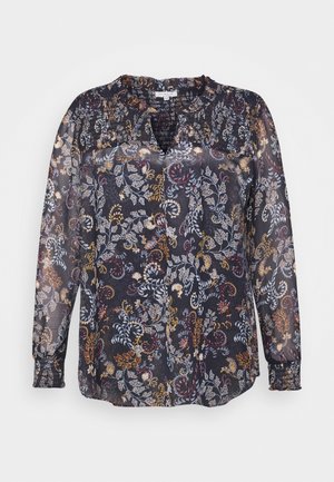 Transparent, mörk blus med ett blommönster i rött, gult och blått. Långa ärmar med samlade manschetter och ett delat halsringning.