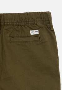 Calças jogger de tecido verde-oliva com cintura elástica e bolso traseiro, apresentando uma etiqueta de marca com o logótipo "JACK&JONES EST.1990".