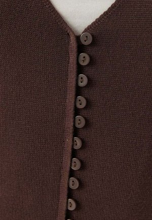 Close-up van bruin gebreide stof met een verticale rij van acht bijpassende bruine knopen langs een V-halsopening.