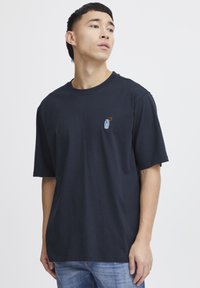 Short-sleeve navy t-shirt made of cotton. Features a small embroidered design on the chest. Round neckline and relaxed fit.