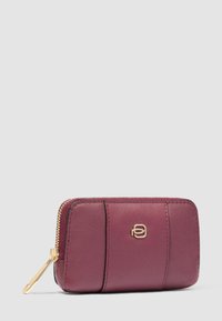 Compact maroon leather wallet with gold zipper and small gold logo centered on front panel against plain background.
