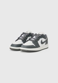 Baskets Nike avec une tige en cuir blanc accentuée de gris, bout rond, design perforé et lacets gris. Semelle en caoutchouc avec un motif texturé.