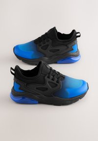 Zwart-blauwe sportschoenen met een soepel verloop in de bovenkant, getextureerde zijkanten en een doorschijnende blauwe zool. Voorzien van veters en een trekkoordje.