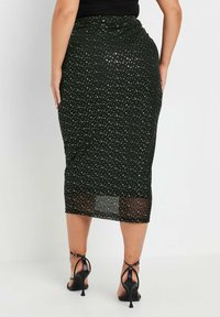 Czarna midi spódnica w białe kropki, wykonana z lekkiego materiału. Posiada siateczkowy dolny brzeg oraz dopasowany krój.