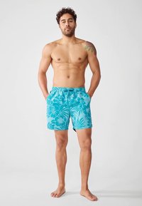 Tyrkysové plavkové šortky s kvetinovým vzorom, vyrobené z ľahkej látky. Majú elastický pás a dve bočné vrecká.