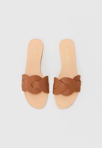 Bruine leren slippertjes met een brede interlockbandontwerp, platte zool en een gladde beige voetbed, met minimalistische accenten.