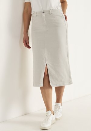 Light gray denim skirt with front slit, fitted design, and belt loops, paired with white sneakers and a plain white top.
