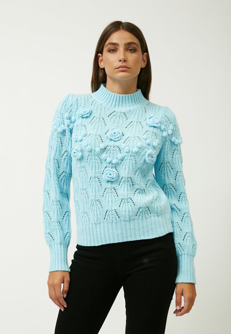 Maglione lavorato a maglia blu chiaro con colletto alto, motivi floreali intricati e texture, e polsini e orlo a coste.