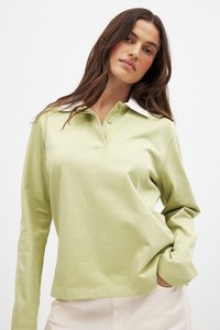 Langarm-Polohemd aus leichtem grünen Baumwollstoff, mit einem weißen Kragen und einer dreiknöpfigen Knopfleiste, lässiger Schnitt und glatter Textur.