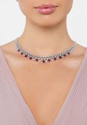 Silver necklace with a teardrop design featuring clear and ruby-colored gems, arranged in a symmetrical pattern around the neck.