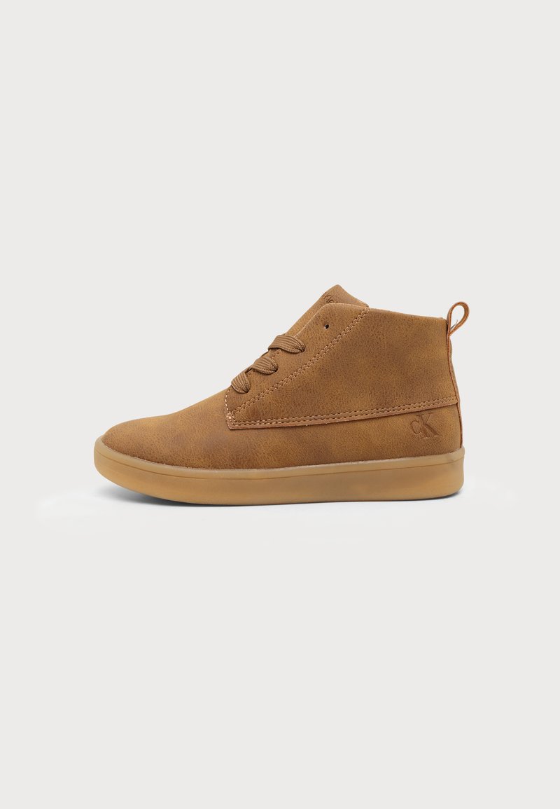Καφέ sneakers μεσαίου ύψους από σουέντ με λαστιχένια σόλα, κορδόνια μπροστά και μικρή θηλιά στη φτέρνα, εμφανιζόμενο σε προφίλ δεξιά σε λευκό φόντο.