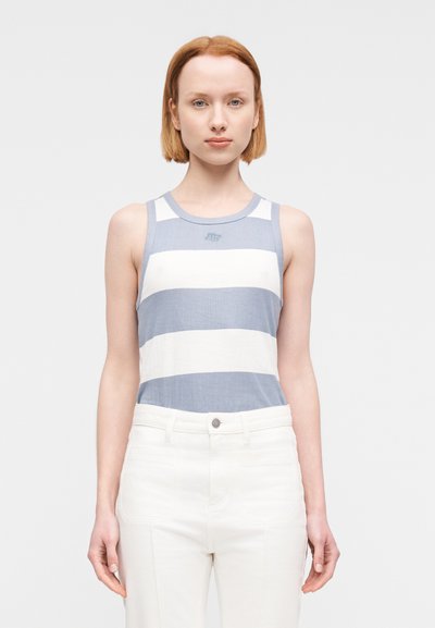 Débardeur rayé bleu et blanc avec une texture côtelée et un col rond, associé à un pantalon blanc avec des poches avant.