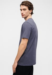 Κοντομάνικο t-shirt με στρογγυλή λαιμόκοψη σε απαλό μωβ χρώμα, κατασκευασμένο από μαλακό βαμβακερό ύφασμα. Διαθέτει χαλαρή εφαρμογή και λεία υφή.