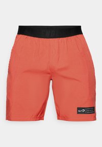 Rote Sportshorts mit einem schwarzen elastischen Bund und einem schwarzen Patch auf dem linken Bein, auf dem "Endless Unlimited Performance" steht.