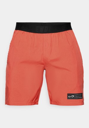 Rote Sportshorts mit einem schwarzen elastischen Bund und einem schwarzen Patch auf dem linken Bein, auf dem "Endless Unlimited Performance" steht.