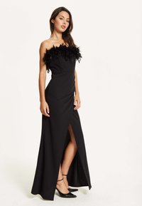 Black evening gown with a strapless design and feather accents at the neckline, featuring a front slit and a fitted silhouette.