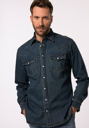 Camisa de mezclilla oscura con mangas largas, cierre frontal de botones, dos bolsillos en el pecho y costuras en contraste. Presenta un diseño de yugo de estilo western.