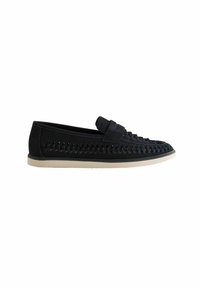 Zapato negro de tejido trenzado tipo slip-on con material de ante, suela plana de goma y un discreto detalle en forma de bucle. Diseño simplista con detalles texturizados.