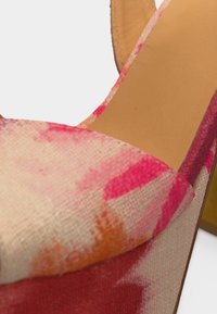 Γυναικείο παπούτσι με ψηλό τακούνι, με επάνω μέρος από ροζ, πορτοκαλί και κόκκινο υφασμάτινο υλικό με υφή και εσωτερική σόλα από δέρμα σε ταμπά απόχρωση, με κοντινή εικόνα του μπροστινού λουριού και της περιοχής της φτέρνας.